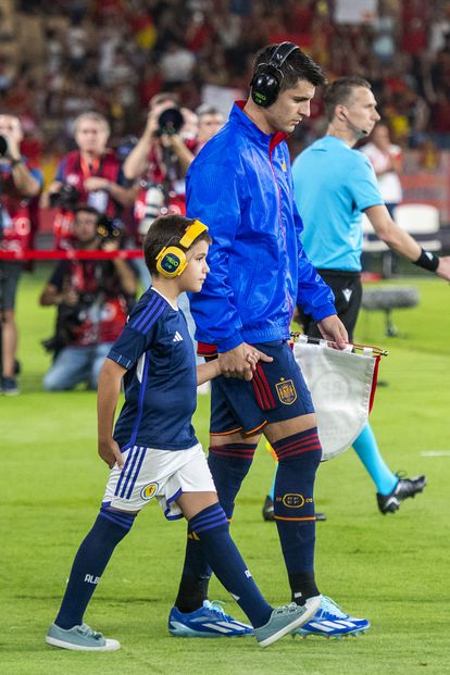 Morata, wearing noise-canceling headphones, jumps onto the field in La Cartuja with an autistic child.